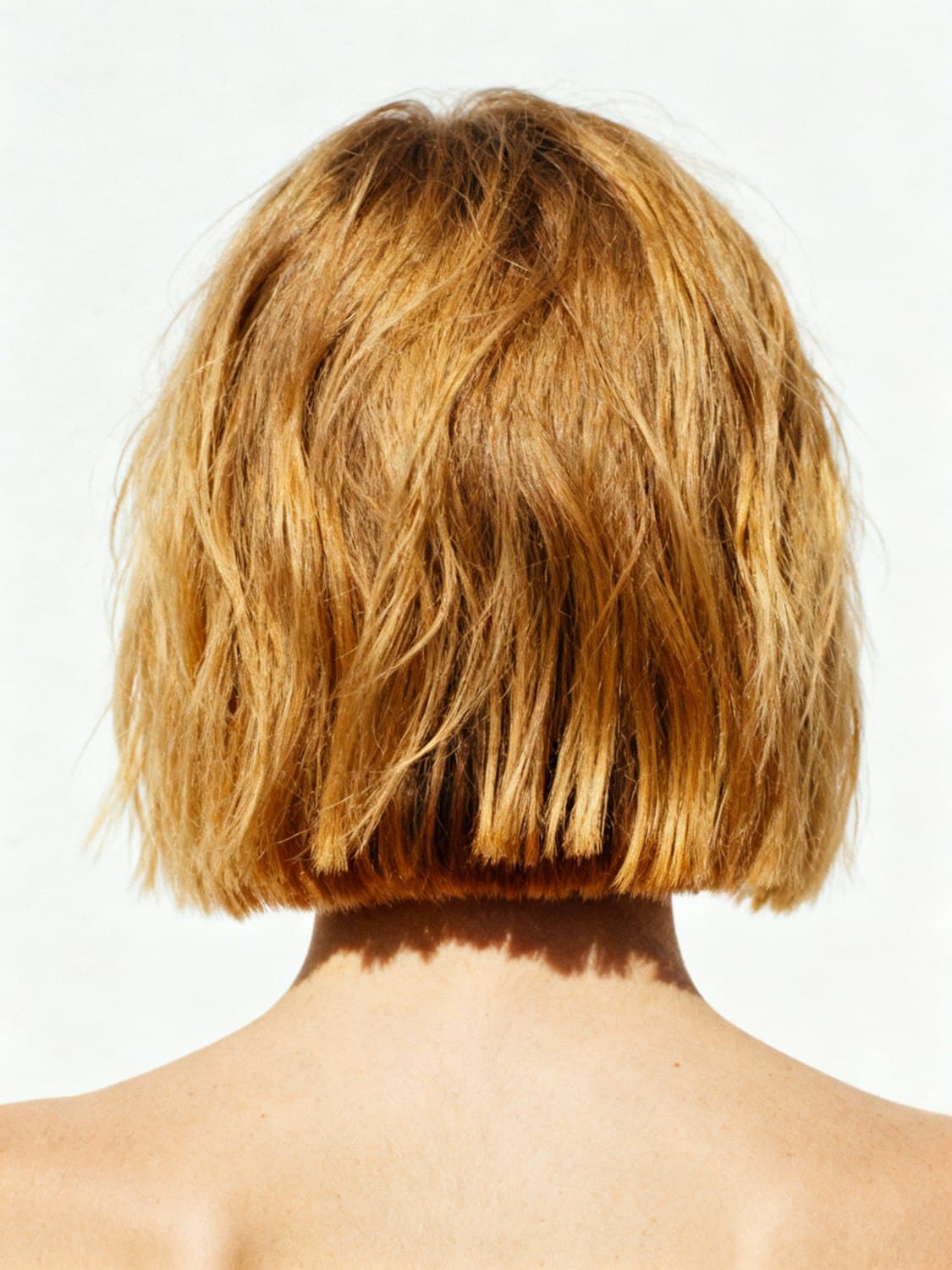 A textured golden bob seen from behind, cut to sit just above the shoulders