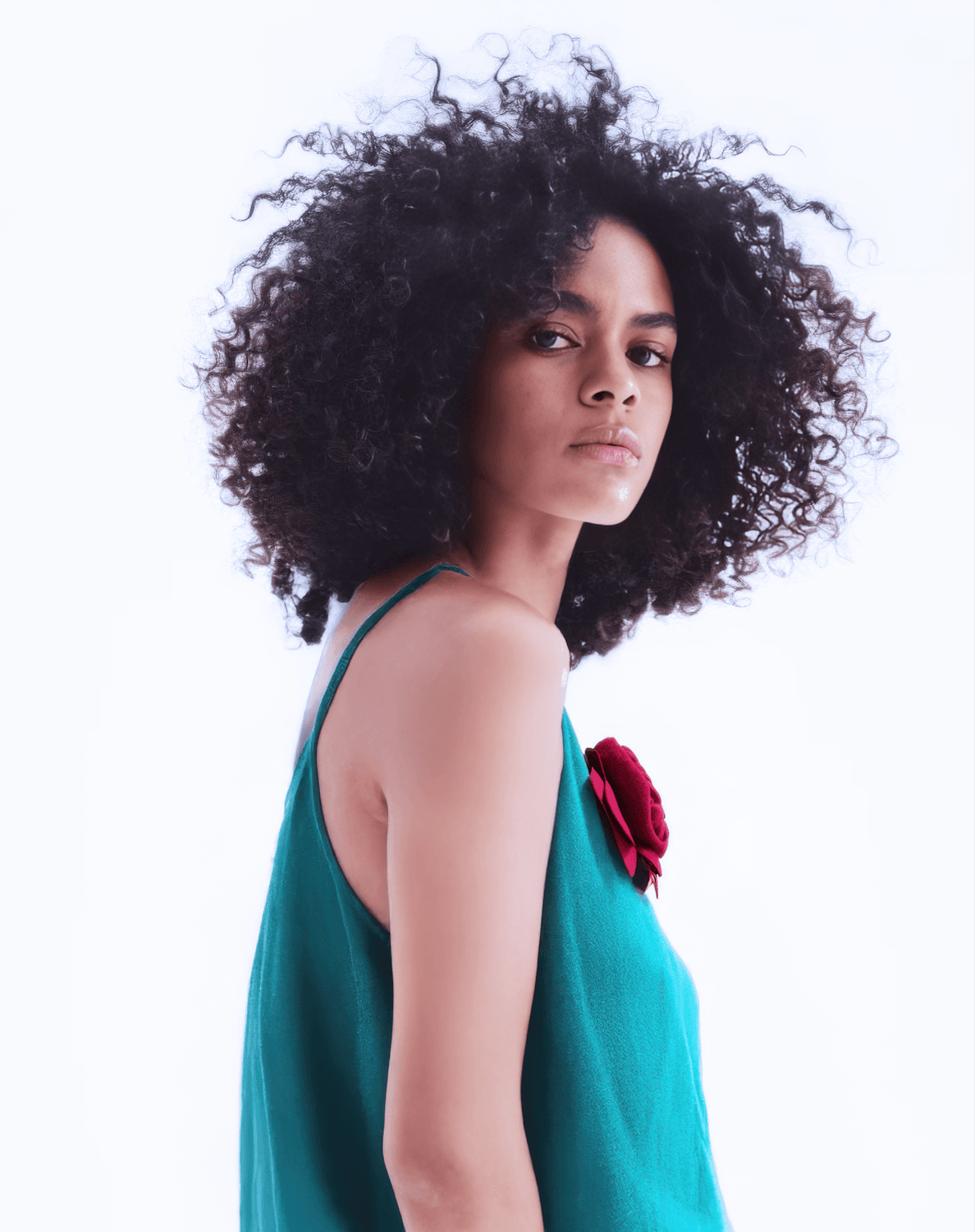 Woman with full, defined natural curls looking over her shoulder